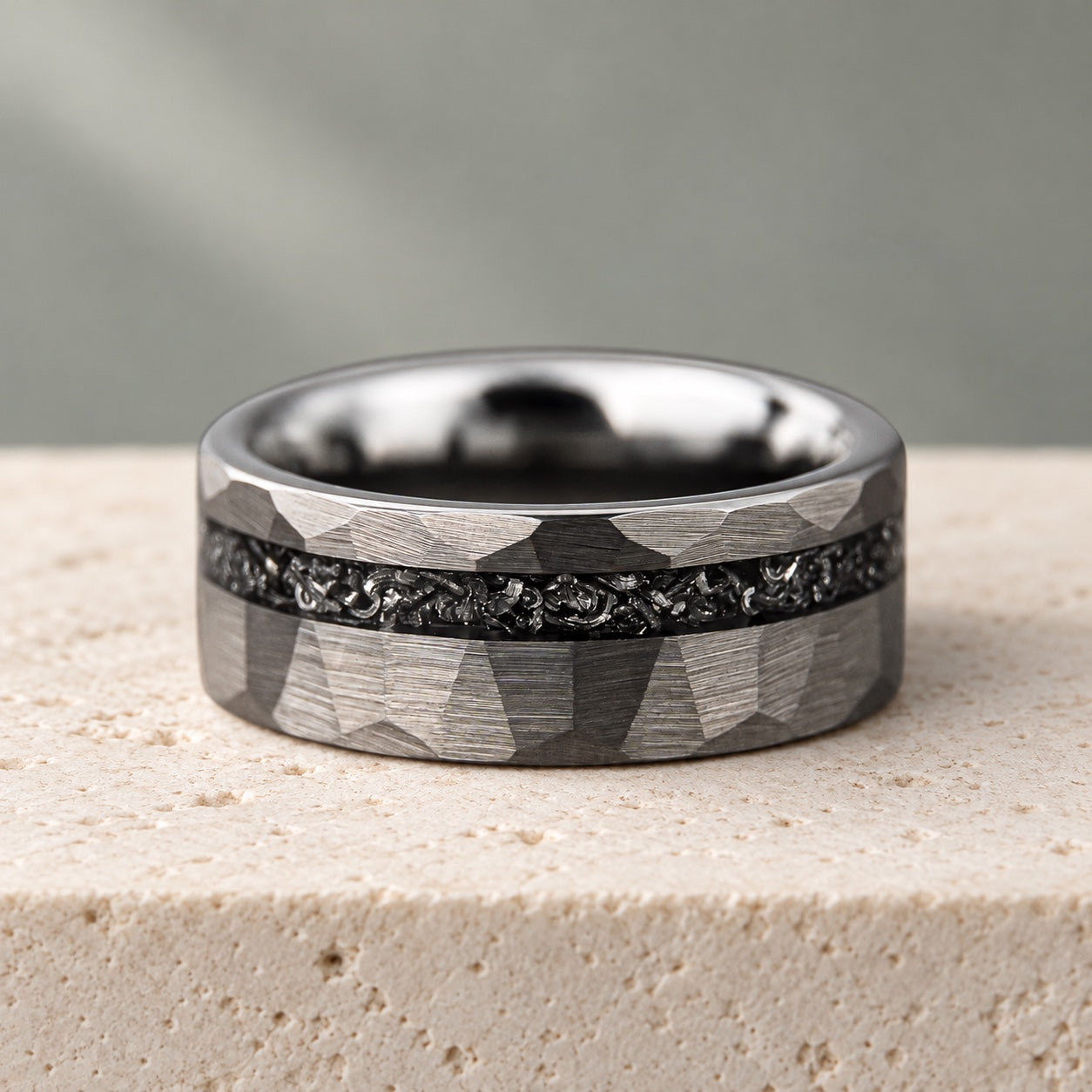 Hammered Birch silver tungsten ring with a dark meteorite inlay on pale limestone